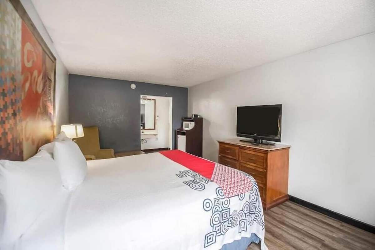 A hotel room with a bed, a television, a desk, and a chair.