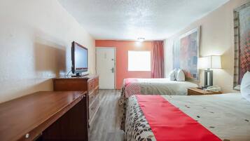 A hotel room with a bed, a desk, a television, and a window with curtains.
