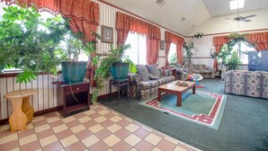 A spacious living room with multiple seating areas, large windows with curtains, and several potted plants. - Hotel O Daylight Inn Elkhart I-90, In (Elkhart)