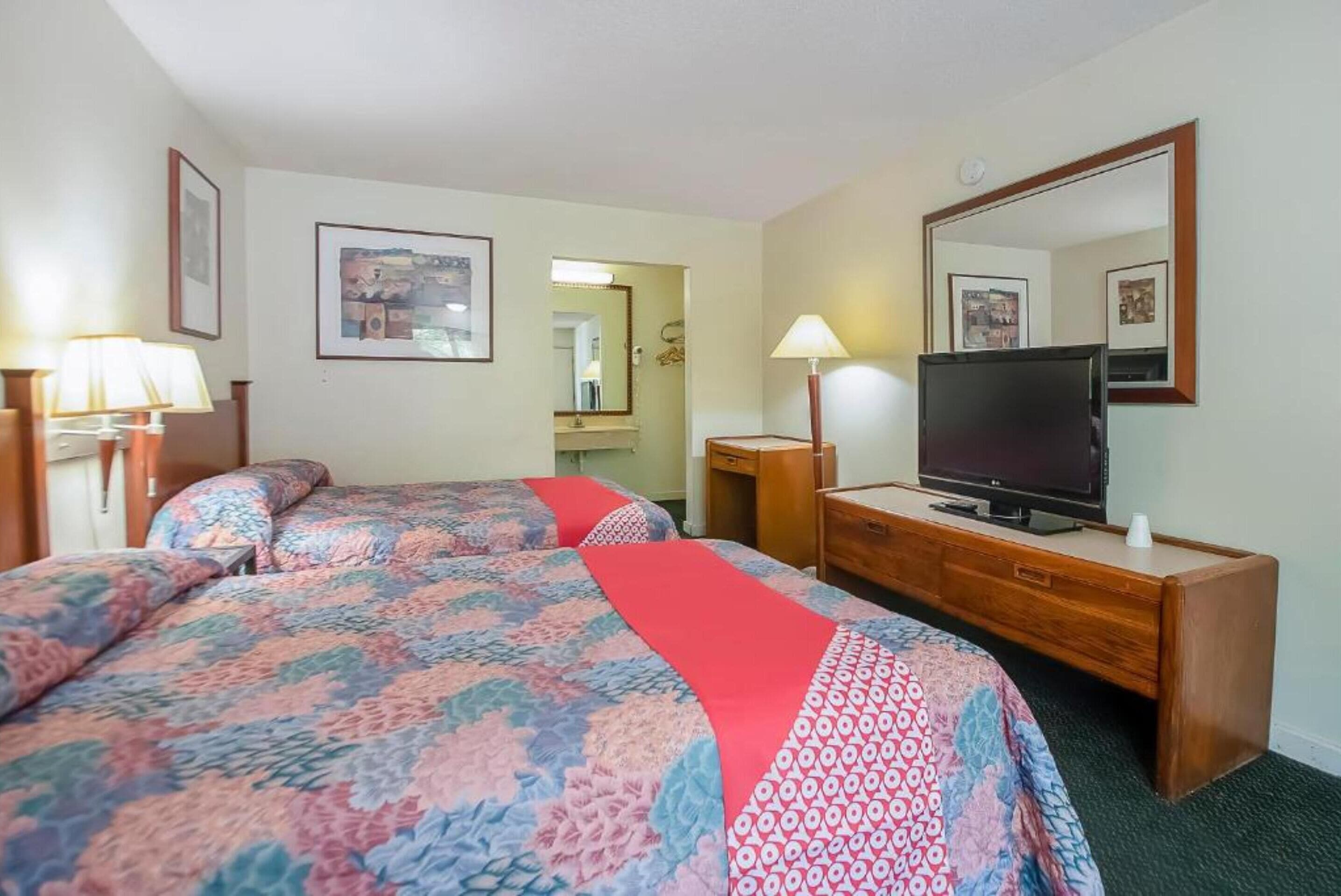 Une chambre d’hôtel avec deux lits, une télévision, une commode et un miroir.