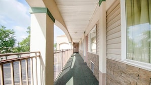 A covered corridor with a metal railing, a brick wall on one side, and a window on the other. - Hotel O Daylight Inn Elkhart I-90, In (Elkhart)