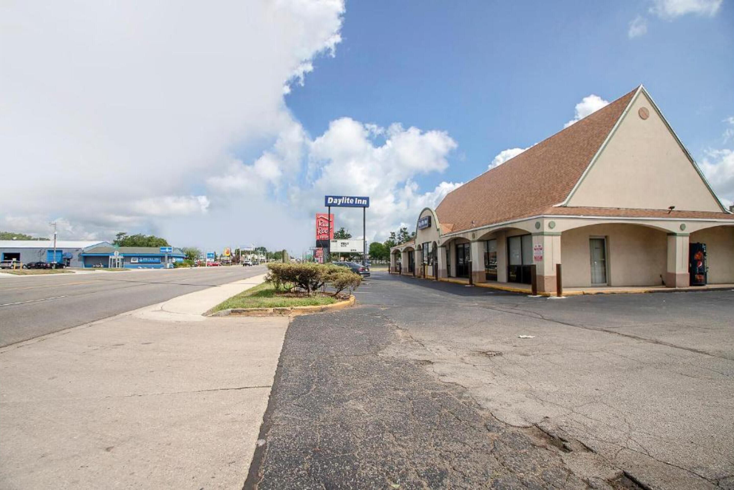 A Paylite Inn with a single-story structure, a parking lot, and a clear sky.