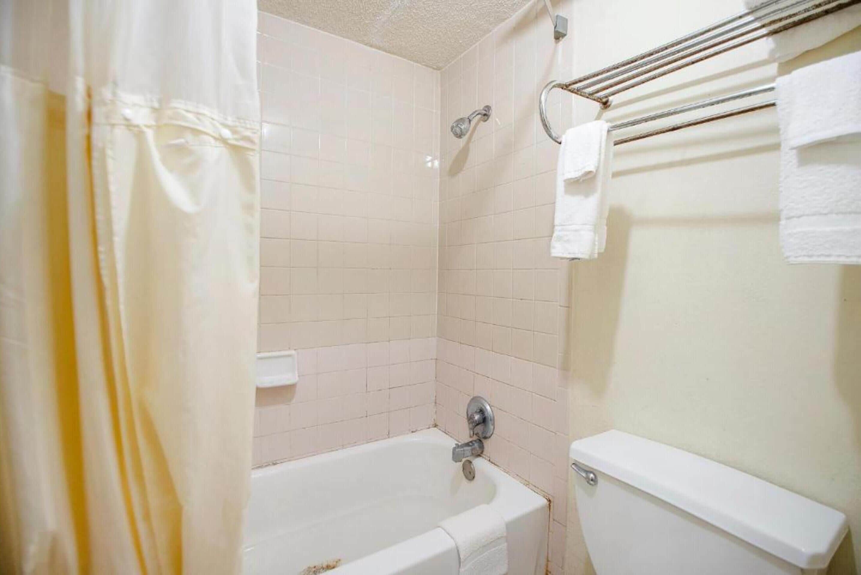 A bathroom with a bathtub, a toilet, and a towel rack.