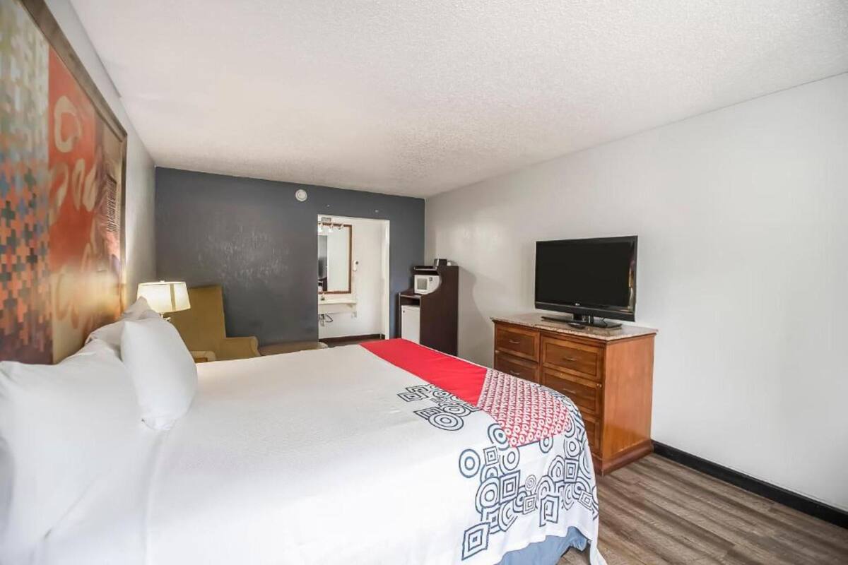 A hotel room with a bed, a television, a desk, and a chair.