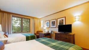 Une chambre d’hôtel avec deux lits, un bureau, une télévision et une fenêtre avec des rideaux.