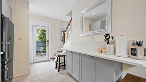 Una cocina con armarios grises, una encimera blanca y un espejo grande sobre el lavabo.