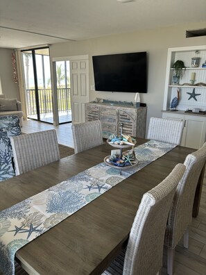 Un espace repas avec une longue table, des chaises en osier et un élément décoratif central.