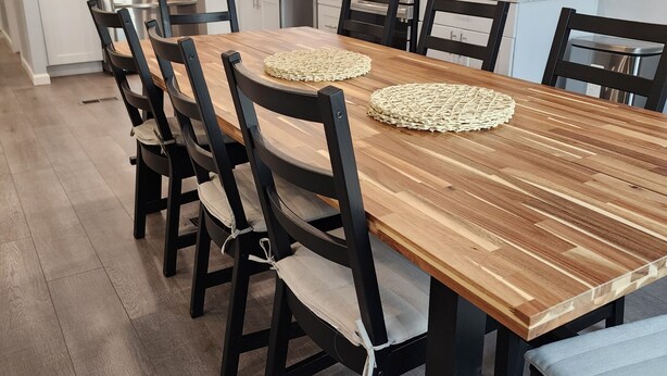 A modern kitchen with white cabinets, stainless steel appliances, and a wooden dining table with chairs. - Red Mesa house  (Page)