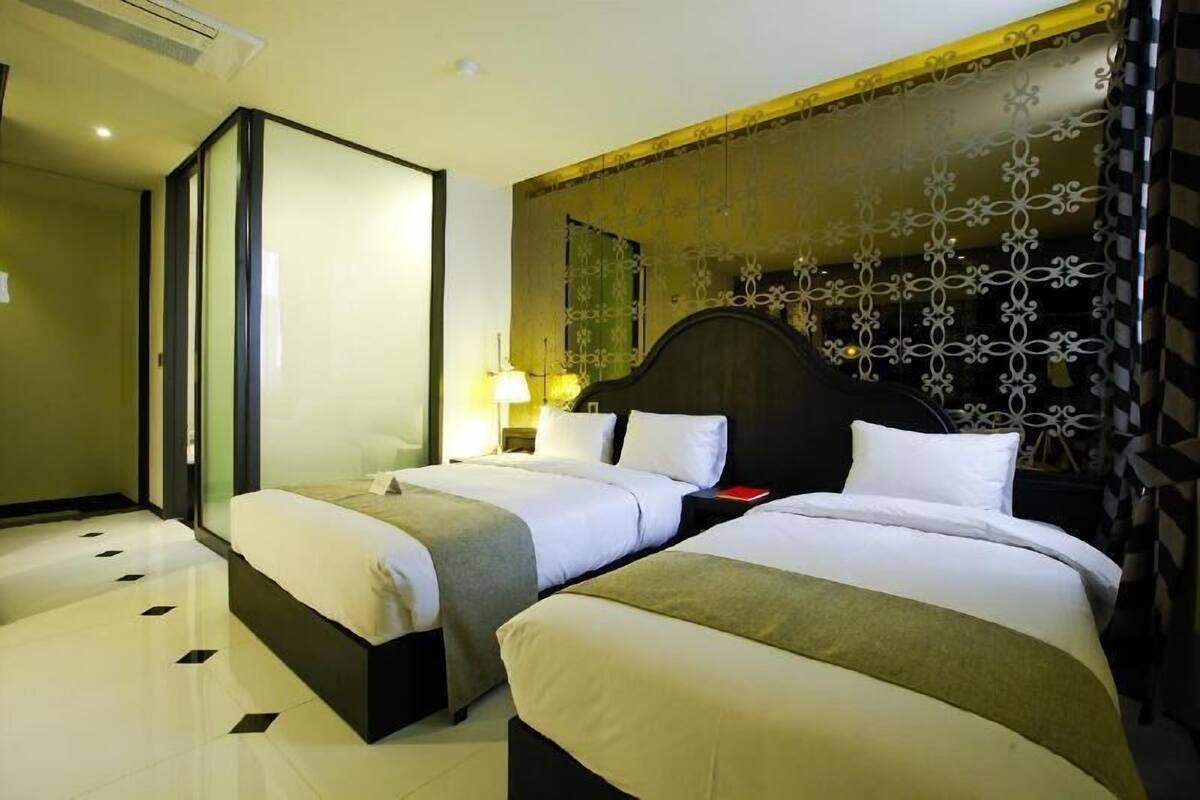 Ein Hotelzimmer mit zwei Betten, einem großen Spiegel und einer dekorativen Wandverkleidung.