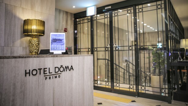 A hotel reception desk with a digital screen, a lamp, and a sign that reads "HOTEL DOMA PRIMO". - Hotel Doma Myeongdong  (Seoul)