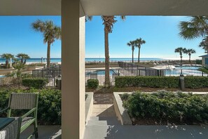 A pool area with palm trees, a clear sky, and a view of the beach. - Bluewater 104 | Gulf Front Garden Condo | Indoor, Outdoor & Kiddie Pool | My Beach Getaways (Orange Beach)