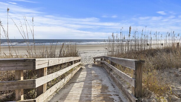 A wooden boardwalk leading to a beach with sand and sparse vegetation. - Contemporary Seascape Villa, Popular Kiawah West Beach, 1BR, Steps to Beach! (Kiawah Island)