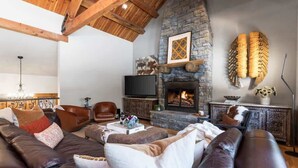 A cozy living room with a stone fireplace, leather sofas, and a television. - Abode at Granite Ridge, luxury lodge, sound system (Teton Village)