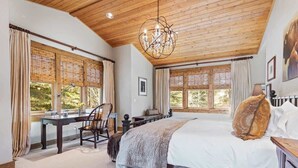A bedroom with a wooden ceiling, a large bed, a desk, and two windows with curtains. - Abode at Granite Ridge, luxury lodge, sound system (Teton Village)