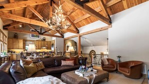 A spacious living area with a large wooden ceiling, a sofa set, a coffee table, and a fireplace. - Abode at Granite Ridge, luxury lodge, sound system (Teton Village)