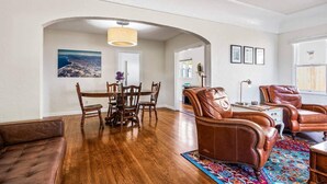 A spacious living room with a wooden dining table, leather sofas, and a colorful rug. - Amazing Reviews, Great Location (Ventura)