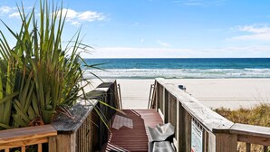 Ein hölzerner Steg führt zu einem Strand mit Blick auf das Meer.