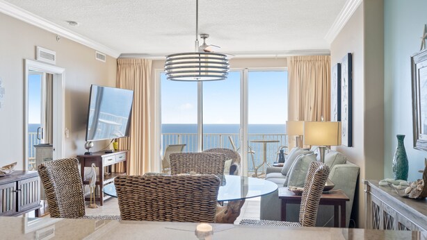 Ein modernes Hotelzimmer mit Balkon, einem runden Esstisch, Korbmöbeln und einem Fernseher.