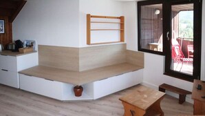 A corner seating area with a wooden bench, a small table, and a wicker chair.