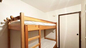 Ein Etagenbett mit einer Leiter, einer Tür und einem kleinen Fenster.