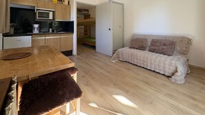 A compact living space with a kitchenette, a sofa, and a bunk bed. - Studio calme pied de pistes (LES ORRES)