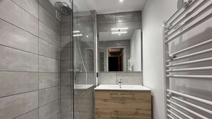 A modern bathroom with a glass shower enclosure, a wooden vanity, and a built-in towel rack. - Studio calme pied de pistes (LES ORRES)