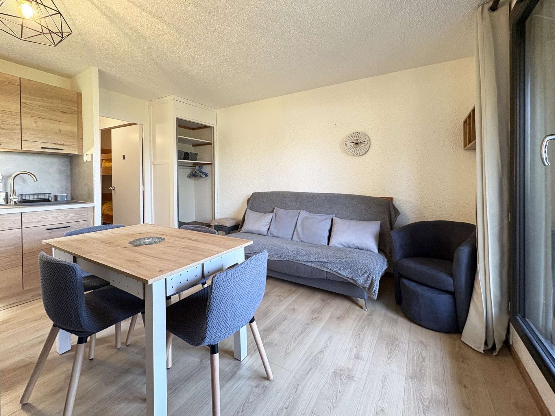 Ein kleiner Wohnbereich mit Küchenzeile, einem Esstisch, einer Couch und einem Sessel.