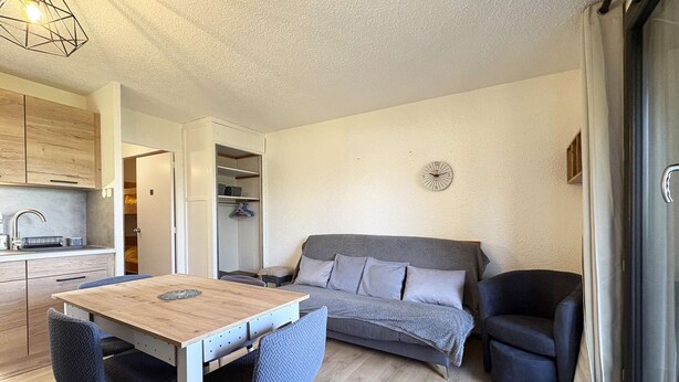 A compact living space with a kitchenette, a dining table, a sofa, and a chair. - 6-person studio with direct access to the slopes (LES ORRES)