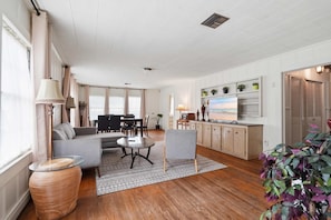A spacious living room with a sofa, a coffee table, and a TV on a cabinet.