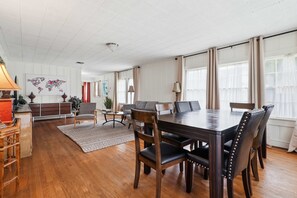 A spacious living area with a wooden dining table, leather chairs, a sofa, and a world map artwork on the wall.