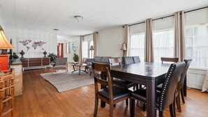 A spacious room with a large wooden dining table, several chairs, a world map on the wall, and a cozy seating area with a sofa and armchairs. - Home Away From Home-4 BR Lafayette Stay in the Heart of Town (Lafayette)