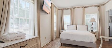 Een hotelkamer met een bed, een televisie, een bureau en een stoel.