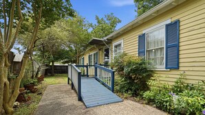 A wooden deck leading to a house with blue shutters, surrounded by greenery and a clear sky. - Home Away From Home-4 BR Lafayette Stay in the Heart of Town (Lafayette)