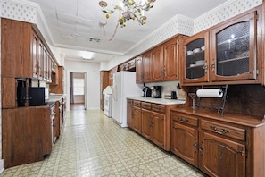 A kitchen with wooden cabinets, a refrigerator, a stove, and a coffee maker.