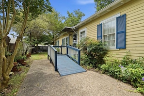 A residential property with a wooden deck leading to a house with blue shutters.