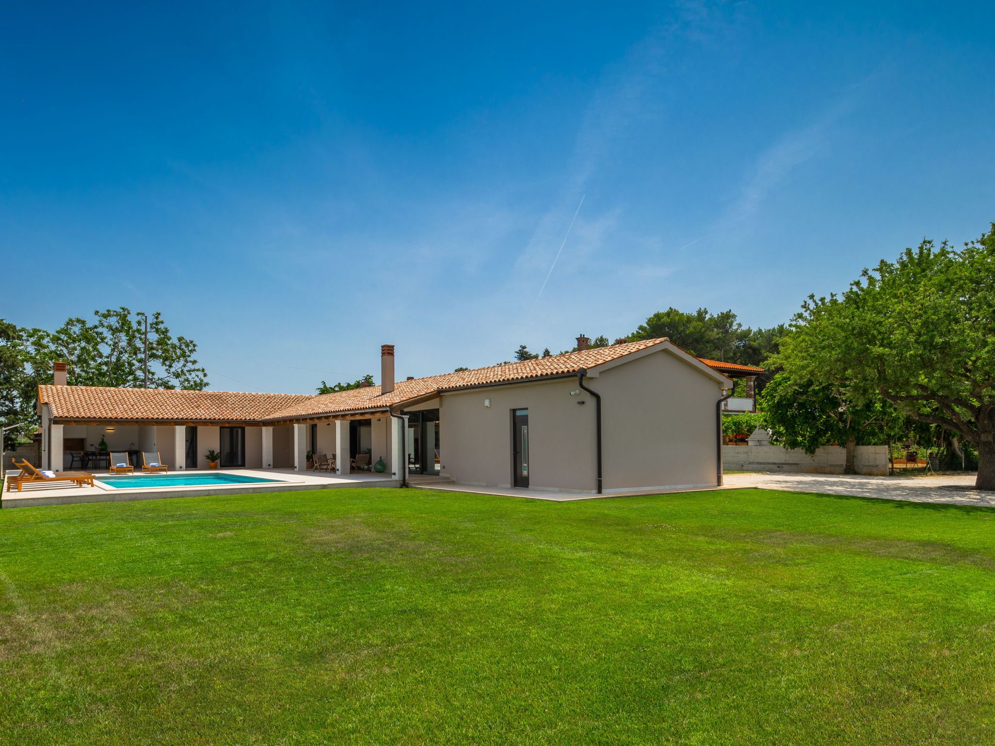 Una casa moderna amb piscina, porxo cobert i un jardí ben cuidat.
