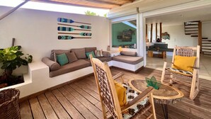 A spacious patio with a wooden ceiling, a sofa set, a dining table, and a chair.