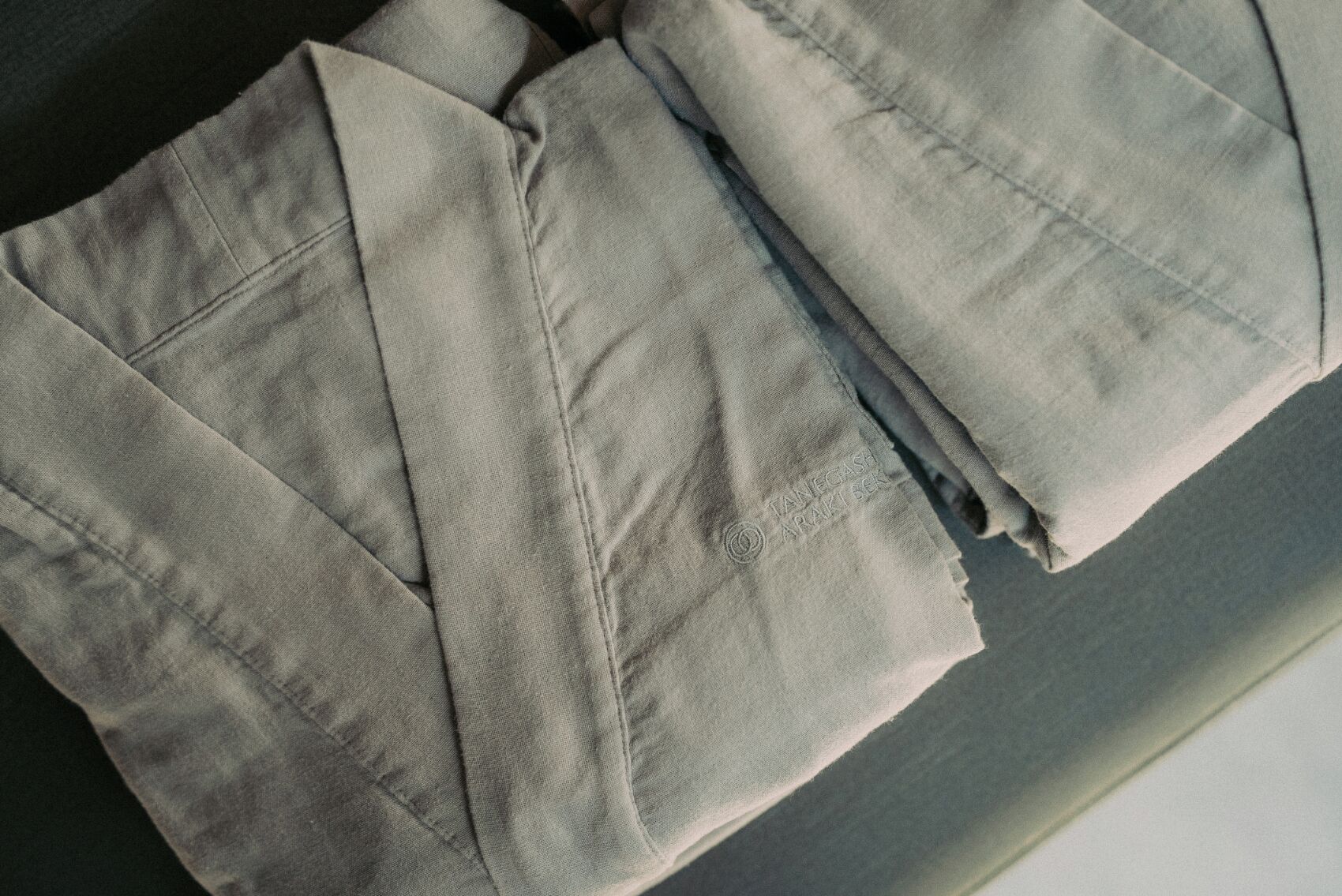 Una camisa gris doblada con un logotipo visible en el puño.