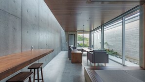 A modern interior with a long wooden bench, a sofa, and a table with chairs.