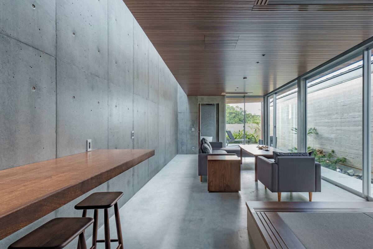 A modern interior with a long wooden bench, a sofa, and a table with chairs.