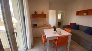 A modern living room with a dining area, a sofa, and a kitchen area with a microwave and coffee maker. - Lovely apartment for 4 guests with WIFI, A/C, TV and balcony (San Michele Al Tagliamento)
