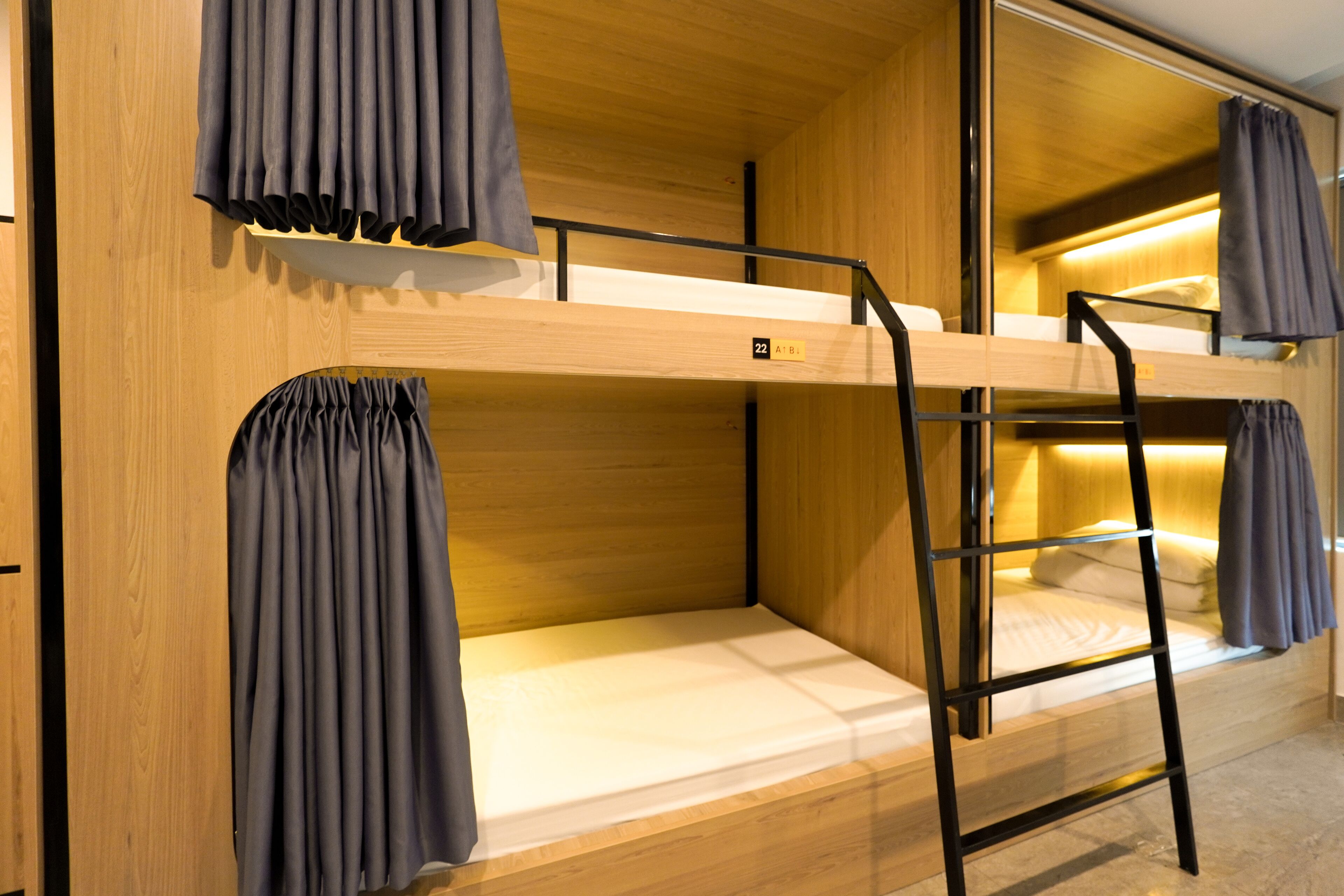 A bunk bed with a wooden frame, a ladder, and curtains.