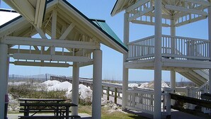 A gazebo with a picnic table, white railings, and a view of the beach.