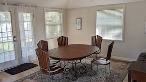 A dining area with a round table, six chairs, a ceiling fan, and a patterned rug. - Gulf Coast Getaway Home-3 bed, 7m walk to bay beach and pier (Mary Esther)