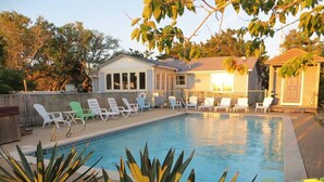 A swimming pool with lounge chairs, a house, and a small shed in the background. - Soundfront Sunsets with Private Dock, Kayaks, Large Pool, Hot Tub, Guesthouse (Salvo)