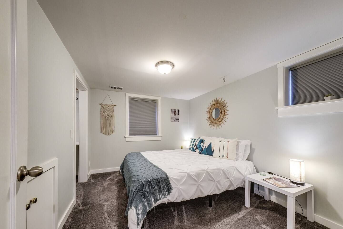 A bedroom with a bed, bedside table, and a window with blinds.