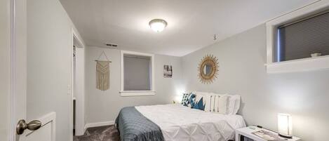 A bedroom with a bed, bedside table, and a window with blinds.
