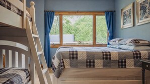 A bedroom with a bunk bed, a window with curtains, a bed with a quilt, and a dresser with drawers. - Heartland Lodge: Multi-fam cabin in Hocking Hills (Logan)