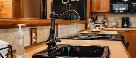 Una cocina con un grifo moderno, un colgador para ollas y una encimera con dispensador de jabón.