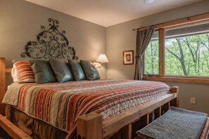A bedroom with a wooden bed, a headboard with a decorative metal design, a window with curtains, and a bedside lamp.